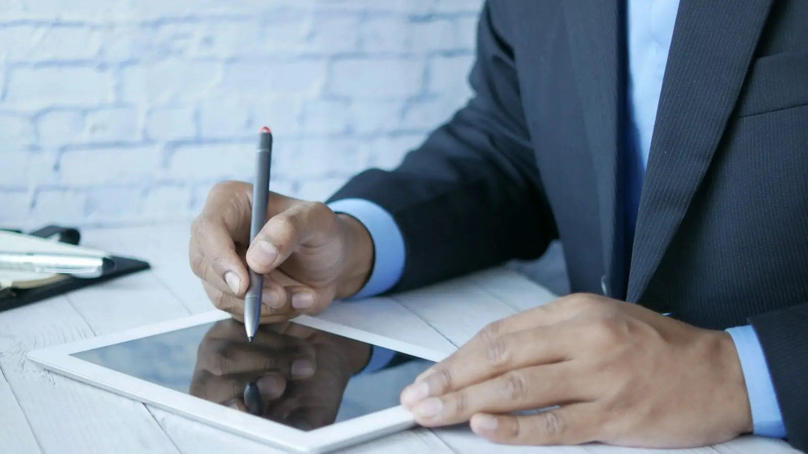 A professional in a suit signing a document on a tablet with a stylus